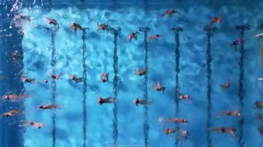 Açık mavi havuzda antrenman yaparken su topu oyuncularının hava görüntüsü. Dinamik hareket ve takım çalışması, spor, su aktiviteleri ve atletik kavramlar için mükemmel olan enerjik bir sahne yaratıyor..