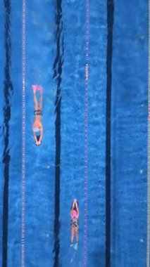 Yüzücülerin açık mavi bir havuzun şeritlerinde süzülen dinamik bir tepeden tırnağa bakış açısı. Kararlılık, atletizm ve su sporları konuları için ideal.