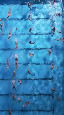 Parlak mavi bir havuzda su topu antrenmanının yukarıdan aşağı görüntüsü. Hareket eden ve su sıçratan oyuncular sporun enerjisini ve koordinasyonunu yakalıyorlar. Takım ve atletik temalar için mükemmel..