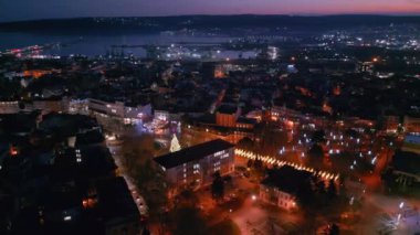 Bulgaristan 'ın Varna kentindeki merkez meydanın çarpıcı bir hava görüntüsü, akşam saatlerinde festival ışıkları ve aydınlatma işaretleriyle çekildi. Seyahat, şehir keşfi için mükemmel bir tema.