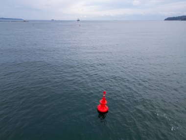 Denizin sakin sularında yüzen kırmızı bir seyir şamandırasının yakın çekim görüntüsü. Şamandıra güvenli seyrüsefer sağlar ve deniz manzarasına canlı bir renk ekler..