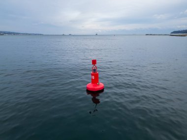 Denizin sakin sularında yüzen kırmızı bir seyir şamandırasının yakın çekim görüntüsü. Şamandıra güvenli seyrüsefer sağlar ve deniz manzarasına canlı bir renk ekler..