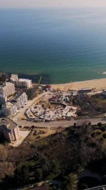 Bulgaristan 'ın Varna kenti yakınlarındaki Kabakum Sahili' nde inşa halindeki yeni otel veya konut kompleksi. Kule vinçleri, metal yapılar ve deniz manzarası bu canlı, güneşli şantiyeyi tanımlar..