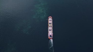 Büyük bir kargo gemisinin havadan görüntüsü. Kırmızı bir yay ile sakin karanlık sularda seyrediyor..