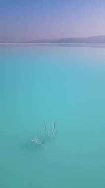 Çimento fabrikasının yanında engebeli tepelerle çevrili bir turkuaz gölet. Canlı su, çorak topraklarla çelişiyor ve çarpıcı bir çevresel etkiye sahip sanayi manzarası yaratıyor..