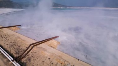 Bir çimento fabrikasının gölü borularla görünür bir şekilde suya atık boşaltıyor. Bu endüstriyel akıntı, kasıtlı olarak boşaltılması ve çevredeki çevresel etkilerinin altını çiziyor.