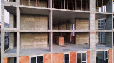 İnşaat halindeki bitmemiş yüksek katlı bir binanın havadan görüntüsü. Yapı, açık beton sütunlar, destek kirişleri ve kentsel iskeletin ham iskeletini gözler önüne seriyor.