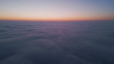 Gün doğumunda bulutların üzerinde uçan dron görüntüsü, kayan sis ve altın ufuk ile yüksek irtifada sisli manzara, nefes kesen sinematik hava görüntüsü gökyüzünün ve bulutların huzur verici güzelliğini yakalıyor
