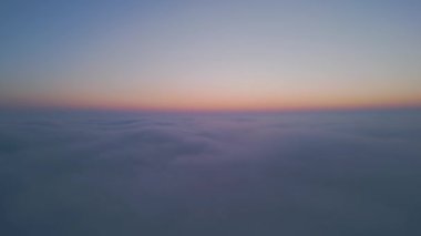 Gün doğumunda bulutların üzerinde uçan dron görüntüsü, kayan sis ve altın ufuk ile yüksek irtifada sisli manzara, nefes kesen sinematik hava görüntüsü gökyüzünün ve bulutların huzur verici güzelliğini yakalıyor