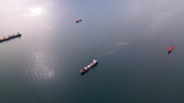 Açık denizde yüzen kargo gemilerine ait hava perspektifi, küresel ticaret ve deniz taşımacılığını temsil ediyor. Sakin su ve dağınık gemiler nakliyenin dinamik görüntüsünü oluşturuyor.