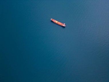 Açık denizde yüzen kargo gemilerine ait hava perspektifi, küresel ticaret ve deniz taşımacılığını temsil ediyor. Sakin su ve dağınık gemiler nakliyenin dinamik görüntüsünü oluşturuyor.