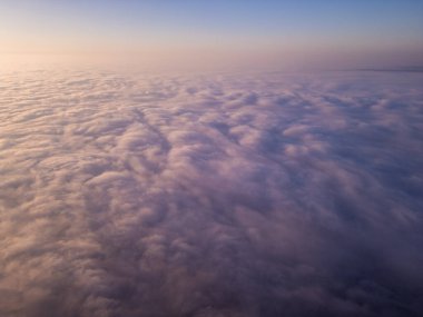 Uçsuz bucaksız bir bulut denizi üzerinde nefes kesici bir gün doğumu manzarası. Altın ışık, yuvarlanan sisin üzerine yumuşak bir parıltı saçar. Pürüzsüz bir hareket ve yüksek irtifa ile rüya gibi, sakin bir atmosfer yaratır.