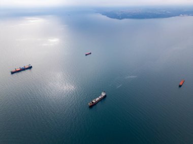 Açık denizde yüzen kargo gemilerine ait hava perspektifi, küresel ticaret ve deniz taşımacılığını temsil ediyor. Sakin su ve dağınık gemiler nakliyenin dinamik görüntüsünü oluşturuyor.