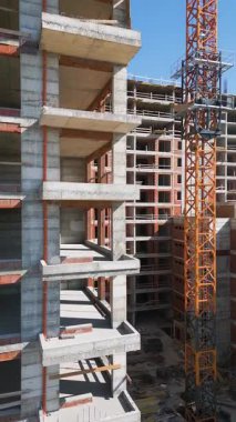 Güneşli bir günde yüksek katlı bir binanın inşaatı. Yapılar, beton iskelet, vinç ve iskelet parlak güneş ışığıyla yıkanarak kentsel gelişimi vurguluyor..