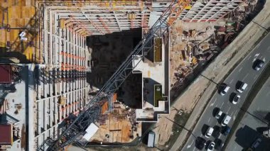 İnşaat alanında kentsel bir alanda parlak güneş ışığı altında canlı malzeme ve ekipmanlar sergileniyor. Havadan yukarıdan aşağıya görünüm.