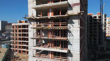 Güneşli bir günde yüksek katlı bir binanın inşaatı. Yapılar, beton iskelet, vinç ve iskelet parlak güneş ışığıyla yıkanarak kentsel gelişimi vurguluyor..