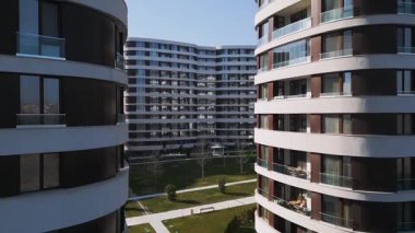 Kahverengi panelleri ve beyaz balkonları olan, temiz mimari çizgileri ve çağdaş kentsel tasarımı ön plana çıkaran modern bir konut binasının insansız hava aracı görüntüsü..