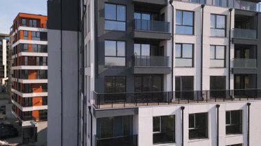 Siyah panelleri ve beyaz balkonları olan, temiz mimari çizgileri ve çağdaş kentsel tasarımı vurgulayan modern bir konut binasının insansız hava aracı görüntüsü..