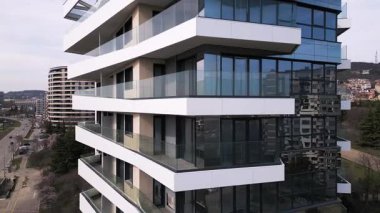 Siyah panelleri ve beyaz balkonları olan, temiz mimari çizgileri ve çağdaş kentsel tasarımı vurgulayan modern bir konut binasının insansız hava aracı görüntüsü..