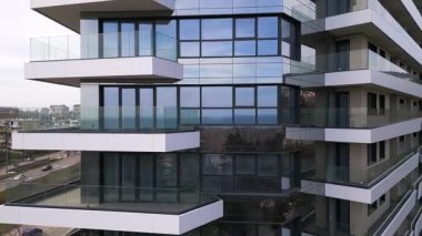 Siyah panelleri ve beyaz balkonları olan, temiz mimari çizgileri ve çağdaş kentsel tasarımı vurgulayan modern bir konut binasının insansız hava aracı görüntüsü..