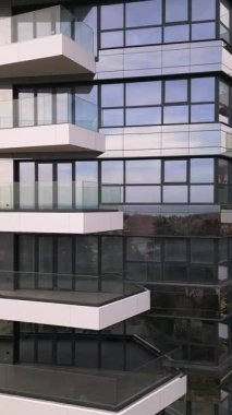 Siyah panelleri ve beyaz balkonları olan, temiz mimari çizgileri ve çağdaş kentsel tasarımı vurgulayan modern bir konut binasının insansız hava aracı görüntüsü..