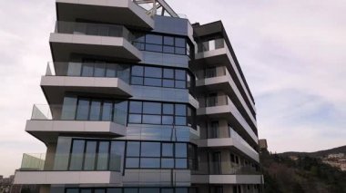 Siyah panelleri ve beyaz balkonları olan, temiz mimari çizgileri ve çağdaş kentsel tasarımı vurgulayan modern bir konut binasının insansız hava aracı görüntüsü..