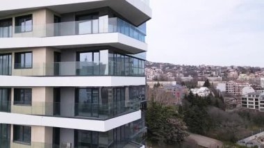 Siyah panelleri ve beyaz balkonları olan, temiz mimari çizgileri ve çağdaş kentsel tasarımı vurgulayan modern bir konut binasının insansız hava aracı görüntüsü..