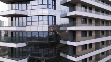Siyah panelleri ve beyaz balkonları olan, temiz mimari çizgileri ve çağdaş kentsel tasarımı vurgulayan modern bir konut binasının insansız hava aracı görüntüsü..