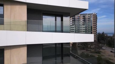 Kahverengi panelleri ve beyaz balkonları olan, temiz mimari çizgileri ve çağdaş kentsel tasarımı ön plana çıkaran modern bir konut binasının insansız hava aracı görüntüsü..