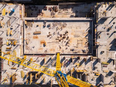 İnşaat alanında kentsel bir alanda parlak güneş ışığı altında canlı malzeme ve ekipmanlar sergileniyor. Havadan yukarıdan aşağıya görünüm.