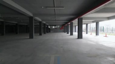 İHA, beton sütunları ve açık kenarları olan boş bir otoparkı yakalıyor. Endüstriyel alan doğal ışıkla aydınlanıyor, modern ama terk edilmiş bir atmosfer yaratıyor..