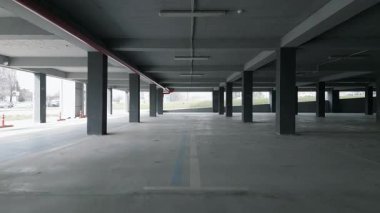 İHA, beton sütunları ve açık kenarları olan boş bir otoparkı yakalıyor. Endüstriyel alan doğal ışıkla aydınlanıyor, modern ama terk edilmiş bir atmosfer yaratıyor..