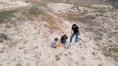 Bir anne ve iki oğlu, metal dedektör ve küreklerle kumlu bir alanda hazine arıyorlar. Sahne, macerayı, aile bağlarını ve keşifleri doğal bir ortamda yakalar..
