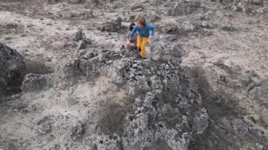 Bir anne engebeli bir arazide büyük bir kayaya tırmanırken çocuğunu destekler. Çocuk zorluğu keşfetmek için uzanır, anne ise rehberlik eder. Eşsiz bir kaya ile vahşi bir ortam.