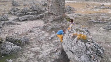 Bir anne engebeli bir arazide büyük bir kayaya tırmanırken çocuğunu destekler. Çocuk zorluğu keşfetmek için uzanır, anne ise rehberlik eder. Eşsiz bir kaya ile vahşi bir ortam.