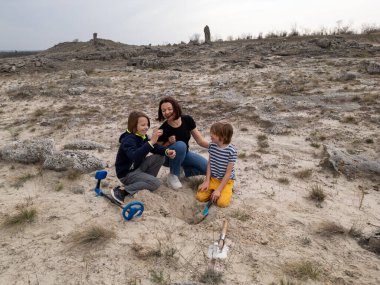 Bir anne ve iki oğlu, metal dedektör ve küreklerle kumlu bir alanda hazine arıyorlar. Sahne, macerayı, aile bağlarını ve keşifleri doğal bir ortamda yakalar..