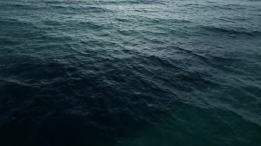 Bu görüntü, sakin bir okyanusun dingin genişliğini, yumuşak gri bulutlardan oluşan bir battaniyenin altında gün geceye, hava görüşüne dönüşürken yakalar.