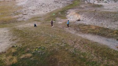 Kadın ve iki çocuk, altın saat boyunca kuru ve kayalık bir arazide planörlerle oynuyorlar. Açık havada eğleniyorlar ve ailecek vakit geçiriyorlar..