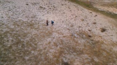 Kadın ve iki çocuk, altın saat boyunca kuru ve kayalık bir arazide planörlerle oynuyorlar. Açık havada eğleniyorlar ve ailecek vakit geçiriyorlar..