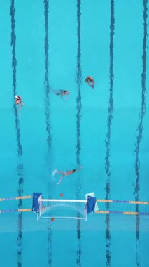 Yüzme havuzunda sutopu antrenmanının en üst görüntüsü. Oyuncular kalenin yanında top ve şerit işaretleriyle antrenman yapıyor..