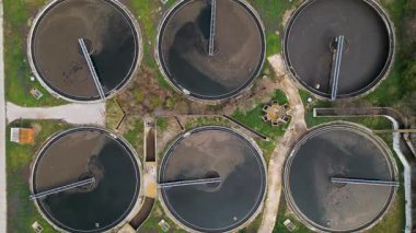 Bir atık su arıtma tesisindeki dairesel tortu tanklarının üst görünümü, geometrik yerleşim ve su arıtma sürecinin altyapısını gösteriyor.
