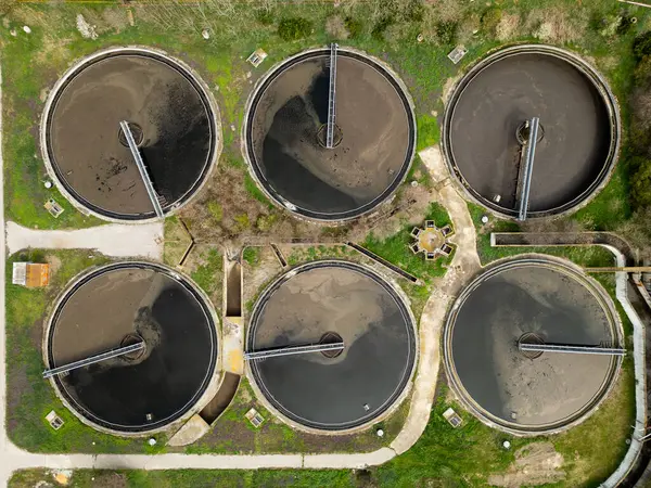 Bir atık su arıtma tesisindeki dairesel tortu tanklarının üst görünümü, geometrik yerleşim ve su arıtma sürecinin altyapısını gösteriyor.