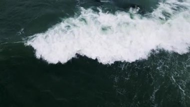 Okyanus dalgalarının çarpışması ve derin yeşil su üzerinde beyaz köpük oluşturması..