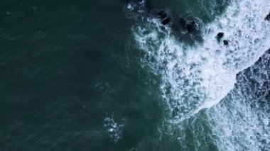 Okyanus dalgalarının çarpışması ve derin yeşil su üzerinde beyaz köpük oluşturması..