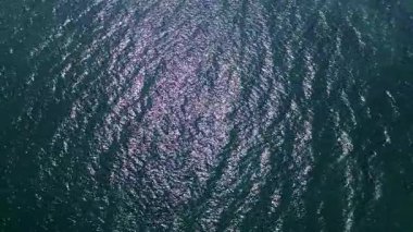 Dalgalanan dalgalar ve güneş yansımalarıyla parıldayan deniz yüzeyinin üst görüntüsü soyut bir doku yaratıyor..