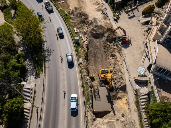 Ağır makineli yol şantiyesinin havadan görünüşü, güvenlik yelekli işçiler ve güneşli bir günde trafiği hareket ettirme.