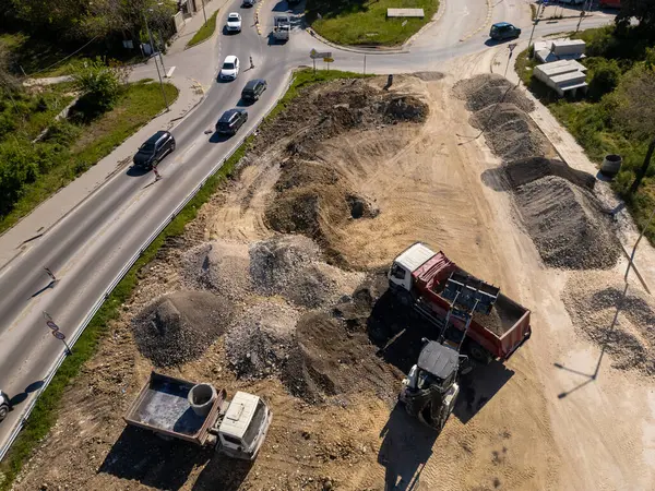 Ağır makineli yol şantiyesinin havadan görünüşü, güvenlik yelekli işçiler ve güneşli bir günde trafiği hareket ettirme.