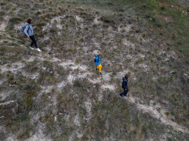 Anne ve iki çocuk bulutlu bir günde vahşi doğada yürüyüş yapıyorlar. Çalılarla ve kayalarla çevrili çimenli bir tepeye çıkıyorlar ve doğal bir çevrede birlikte vakit geçiriyorlar..