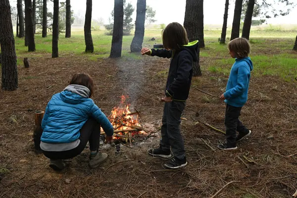 Anne ve iki çocuk ormanda bir kamp ateşinin yanında oturur, küçük bir masada yemek yer ve dinlenirler. Çam ağaçları ve doğa ile çevrili sıcak bir açık hava yemeğinden ve aile zamanından hoşlanırlar..