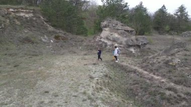 Anne ve iki çocuk bulutlu bir günde vahşi doğada yürüyüş yapıyorlar. Çalılarla ve kayalarla çevrili çimenli bir tepeye çıkıyorlar ve doğal bir çevrede birlikte vakit geçiriyorlar..